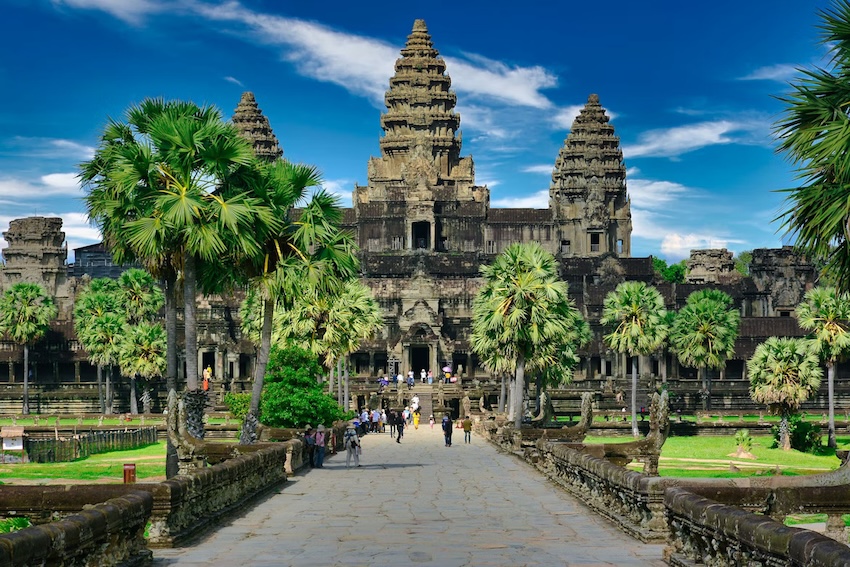 Angkor Wat temple entrance with palm trees and visitors in Cambodia