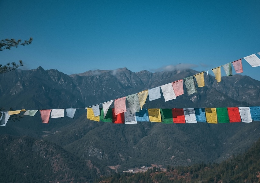 Colorful Bhutanese prayer flags overlooking a mountain range in Bhutan