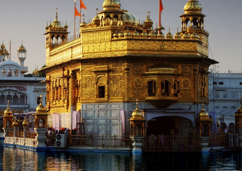 Close-up view of the Golden Temple’s ornate golden architecture beside the sacred water in Amritsar, India.
