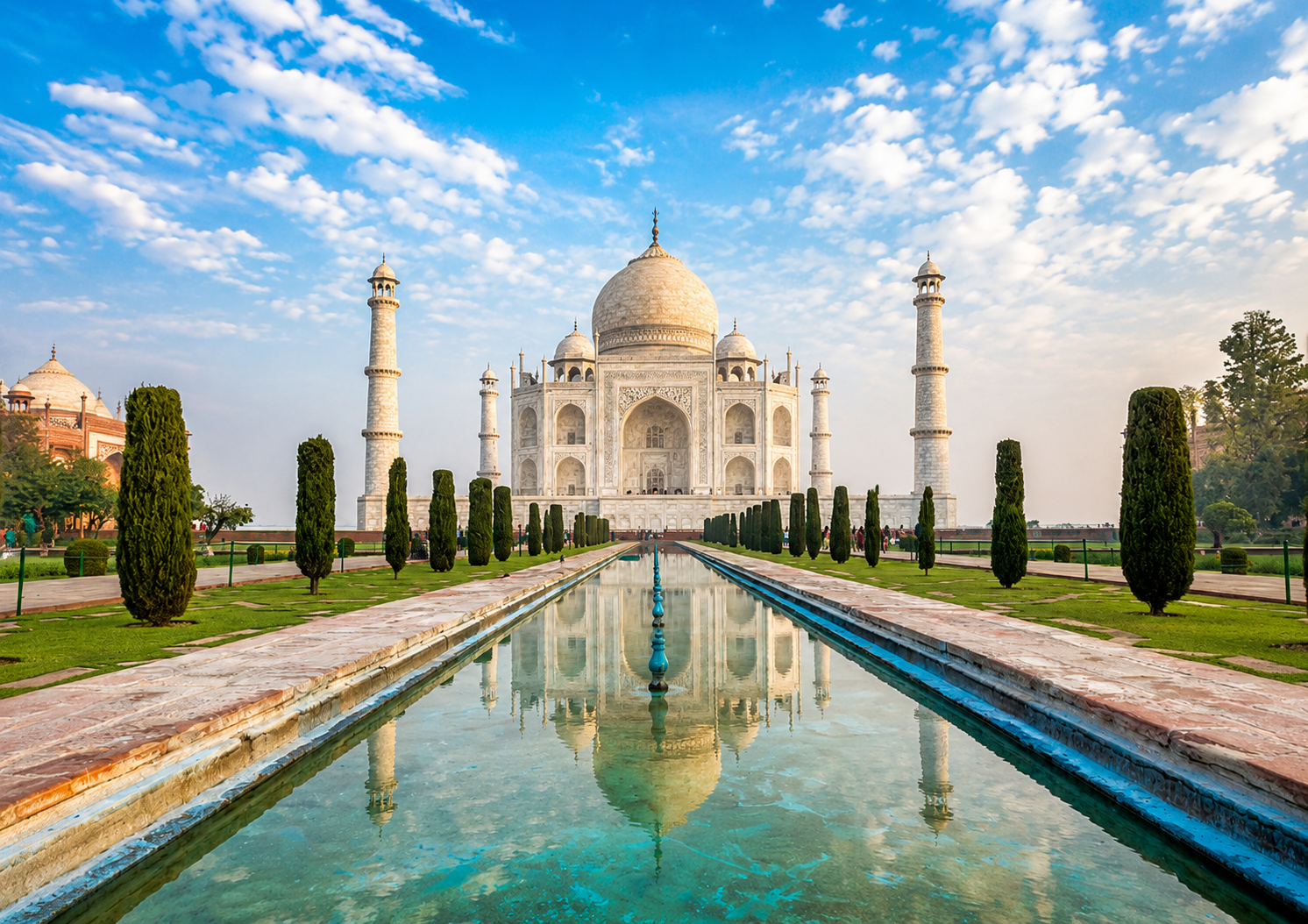 Taj Mahal in Agra, India, reflected in the long water channel under a bright blue sky.