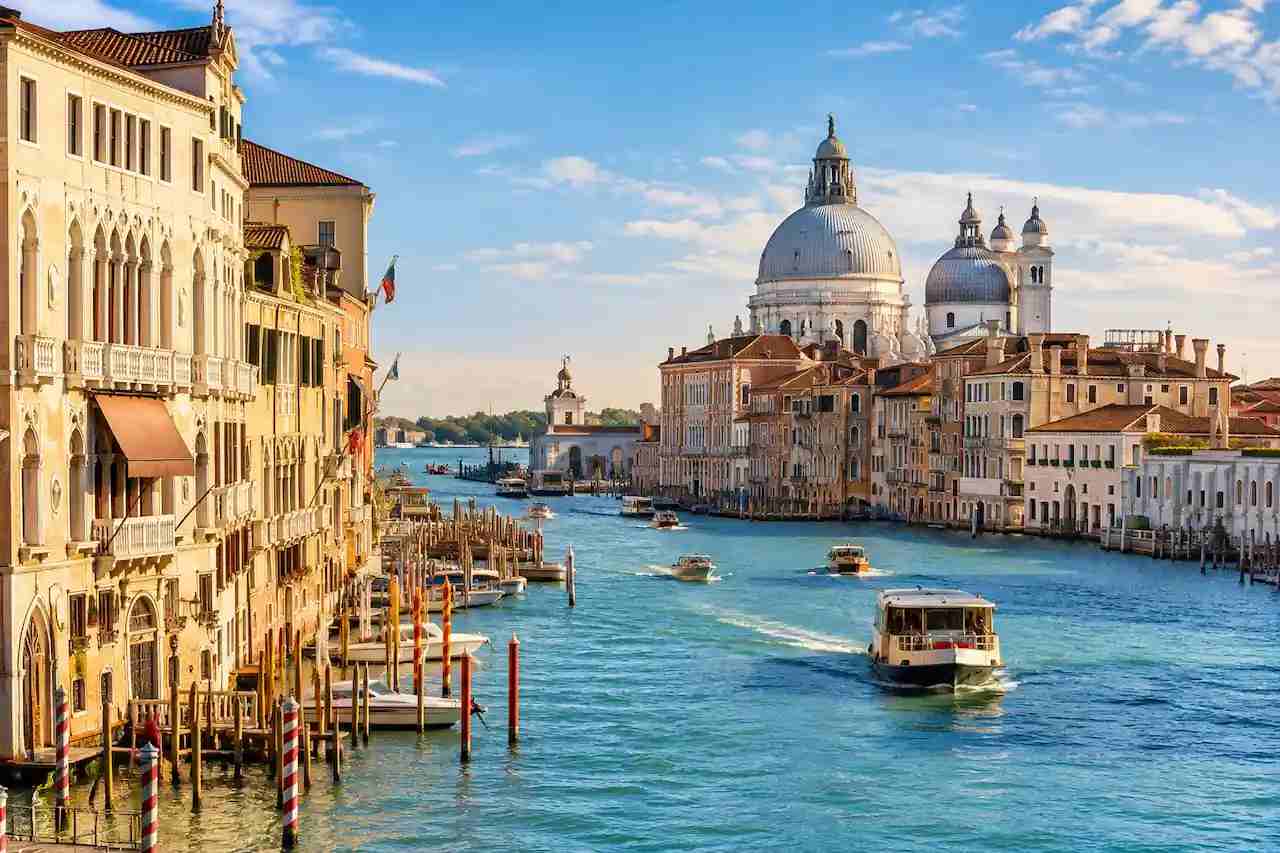 Historic buildings and boats along the Grand Canal in Venice, Italy, on a sunny European holiday.